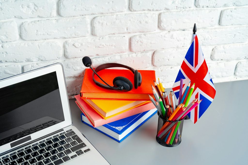 Laptop and flag of UK on desk. English language learning concept